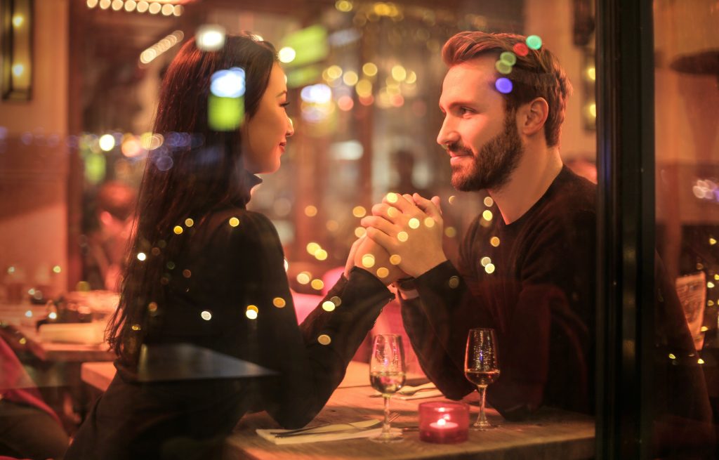A man and a woman hold hands looking at each other at a restaurant