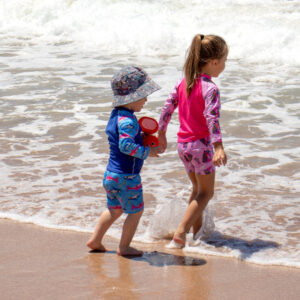 two kids in swimwear by the beach