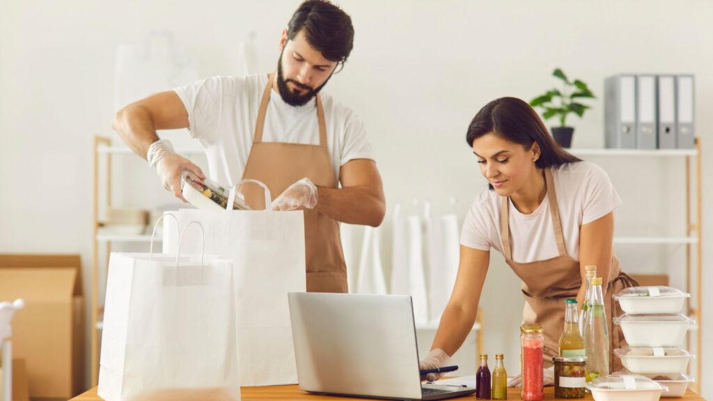 A guy and a girl are wearing aprons while preparing and planning their food and groceries