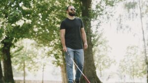 A person who is blind doing a walk in a park