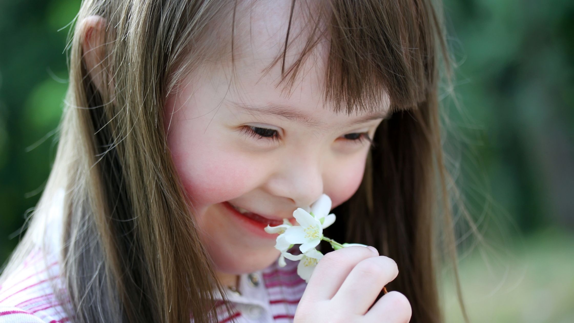 a young girl smelling a flower