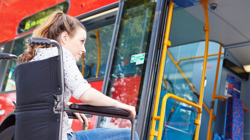 A lady in a wheelchair is about to ride a bus