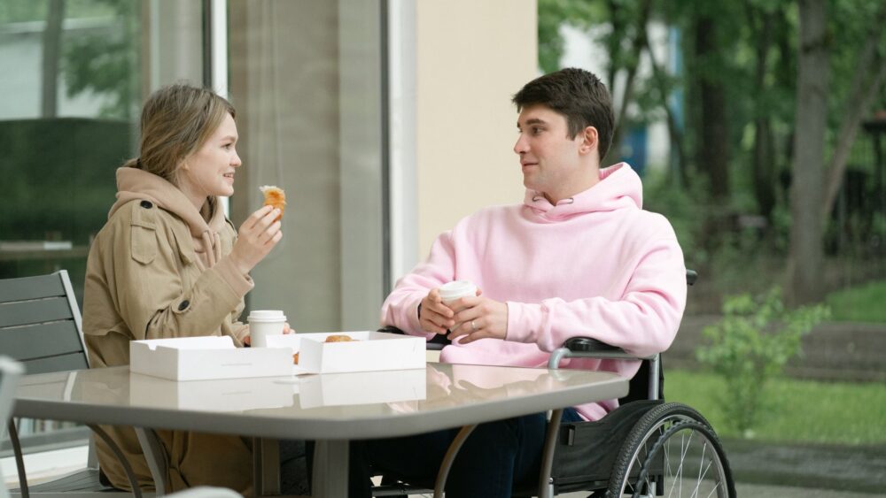 a girl talking to a guy in a wheelchair