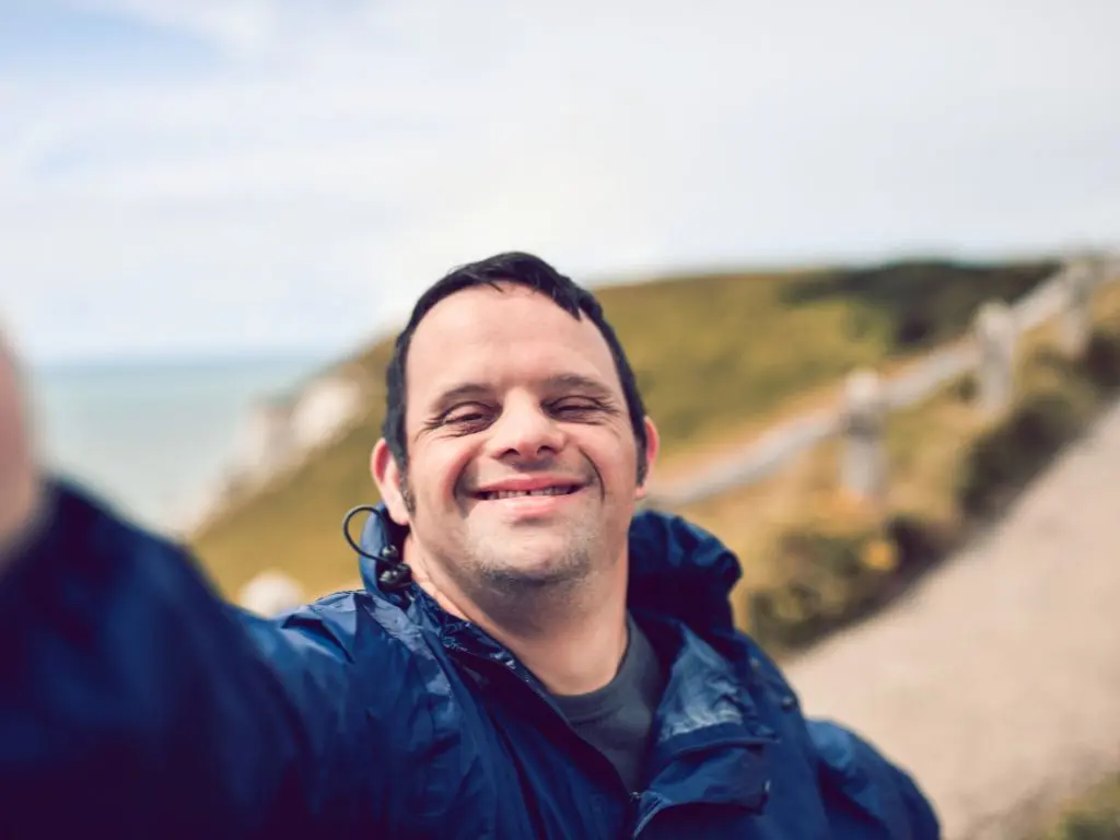 A young man living with disability taking a selfie on the coast